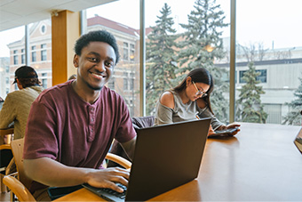 Man working on laptop and smiling at the camera.